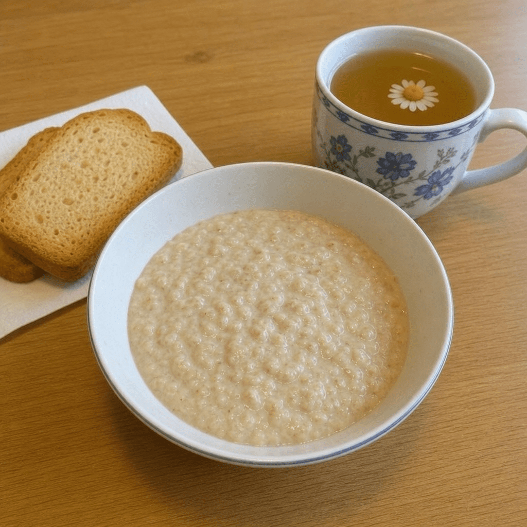 Eine Schüssel mit Haferschleim, daneben Zwieback und eine Tasse Kamillentee